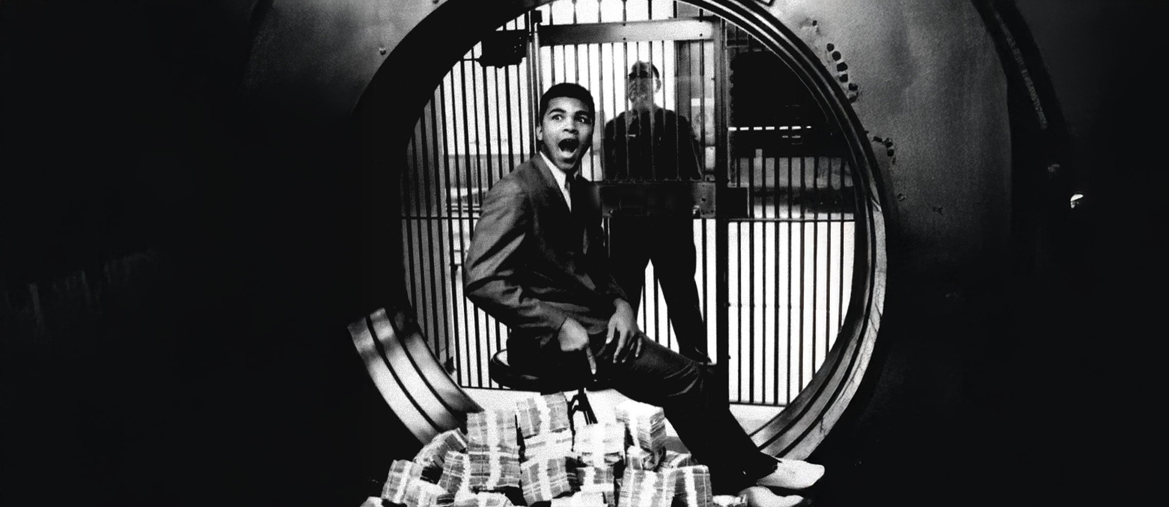 Photo: Howard L. Bingham – Muhammad Ali in a bank vault with cash during a photoshoot.