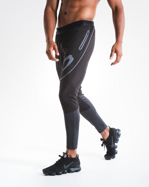 Man in slim fitting black lightweight tracksuit bottoms with reflective detailing and side zipped pockets