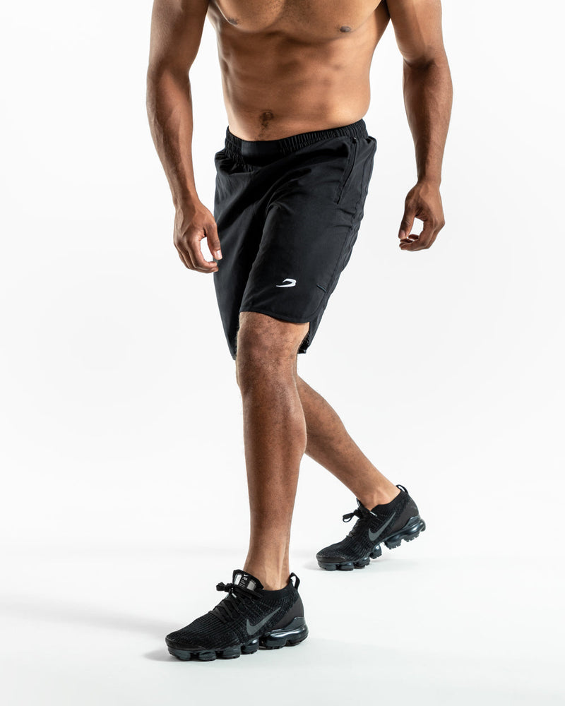 Man in black training shorts with adjustable waistband and side zipped pockets as well as an embroidered white boxraw strike logo.