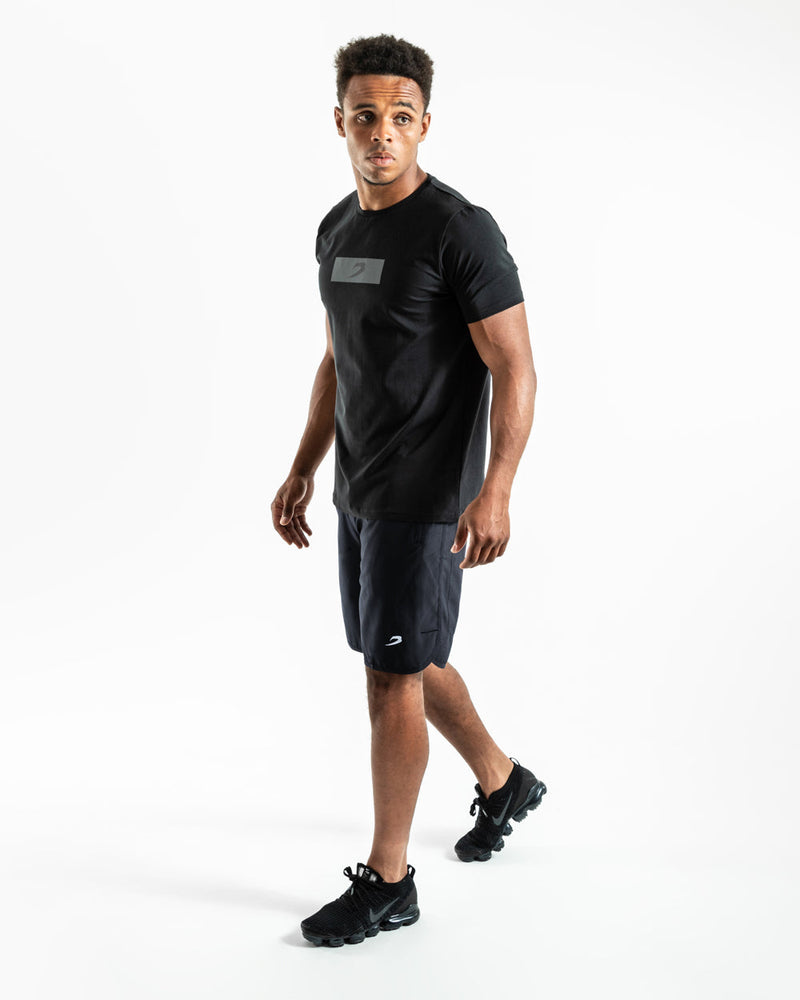 Man in black training shorts with adjustable waistband and side zipped pockets as well as an embroidered white boxraw strike logo.